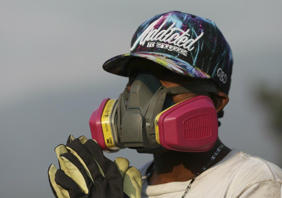 An anti-government Venezuelan migrant wearing protective gear rests from confrontations with Venezuelan National Guards who are blocking the Simon Bolivar International Bridge, in La Parada near Cucuta, Colombia, Sunday, Feb. 24, 2019, on the border with Venezuela. A U.S.-backed drive to deliver foreign aid to Venezuela on Saturday met strong resistance as troops loyal to President Nicolas Maduro blocked the convoys at the border and fired tear gas on protesters. (AP Photo/Fernando Vergara)
