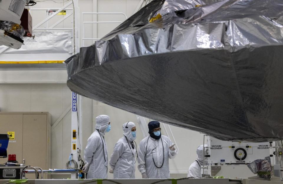 Engineers and technicians under a high gain antenna work on NASA's Europa Clipper