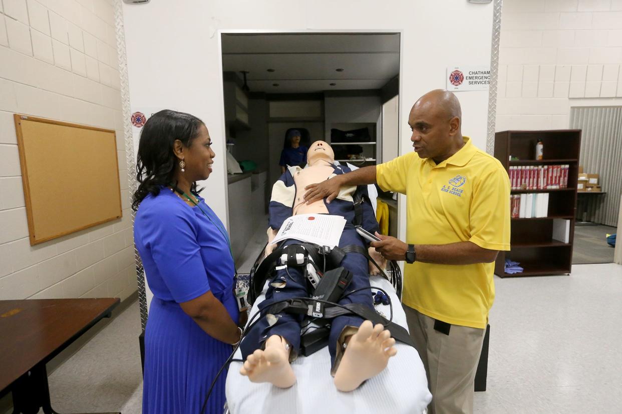 Tijuana Milton, Allied Health and Medical Choice Program coordinator,talks with Superintendent Denise Watts as he demonstrates the dummy used to give students a simulated experience of working with a patient during a tour of the Medical Choice Program classrooms at A.E. Beach High School. 