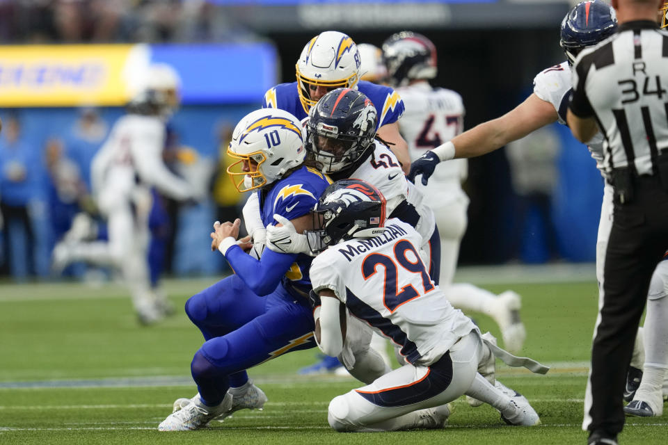 Los Angeles Chargers quarterback Justin Herbert (10) is sacked by Denver Broncos cornerback Ja'Quan McMillian (29) and linebacker Nik Bonitto (42) during the first half of an NFL football game Sunday, Dec. 10, 2023, in Inglewood, Calif. (AP Photo/Marcio Jose Sanchez)
