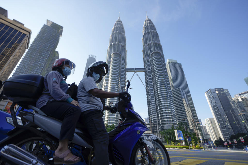 Motorists wearing face masks wait in front of the Twin Towers during the first day of Full Movement Control Order (MCO) in Kuala Lumpur, Malaysia, Tuesday, June 1, 2021. Malls and most businesses in Malaysia shuttered Tuesday as the country began its second near total coronavirus lockdown to tackle a worsening pandemic that has put its healthcare system on the verge of collapse. (AP Photo/Vincent Thian)