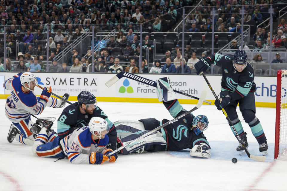 Seattle Kraken defenseman Jamie Oleksiak, right, moves the puck after goaltender Joey Daccord (35) fell to the ice while defending against a shot by Edmonton Oilers left wing Zach Hyman, left, during the second period of an NHL hockey game Saturday, Nov. 11, 2023, in Seattle. (AP Photo/Jason Redmond)