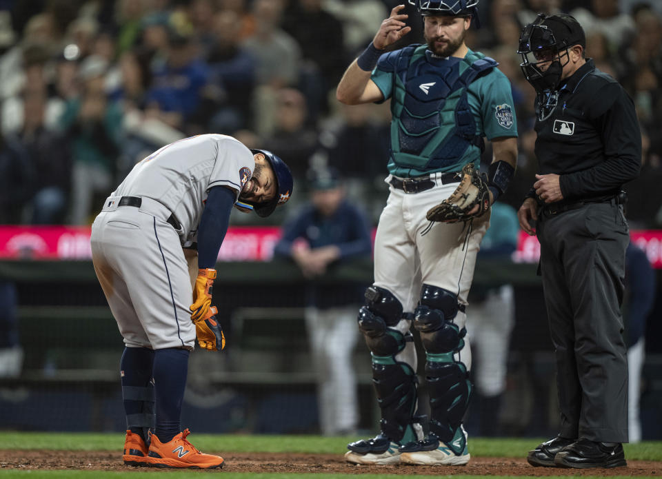 Houston Astros' Jose Altuve, left, reacts after getting hit by a pitch during the ninth inning of a baseball game against the Seattle Mariners, Monday, Sept. 25, 2023, in Seattle. Mariners catcher Cal Raleigh, second from right, looks on. (AP Photo/Stephen Brashear)