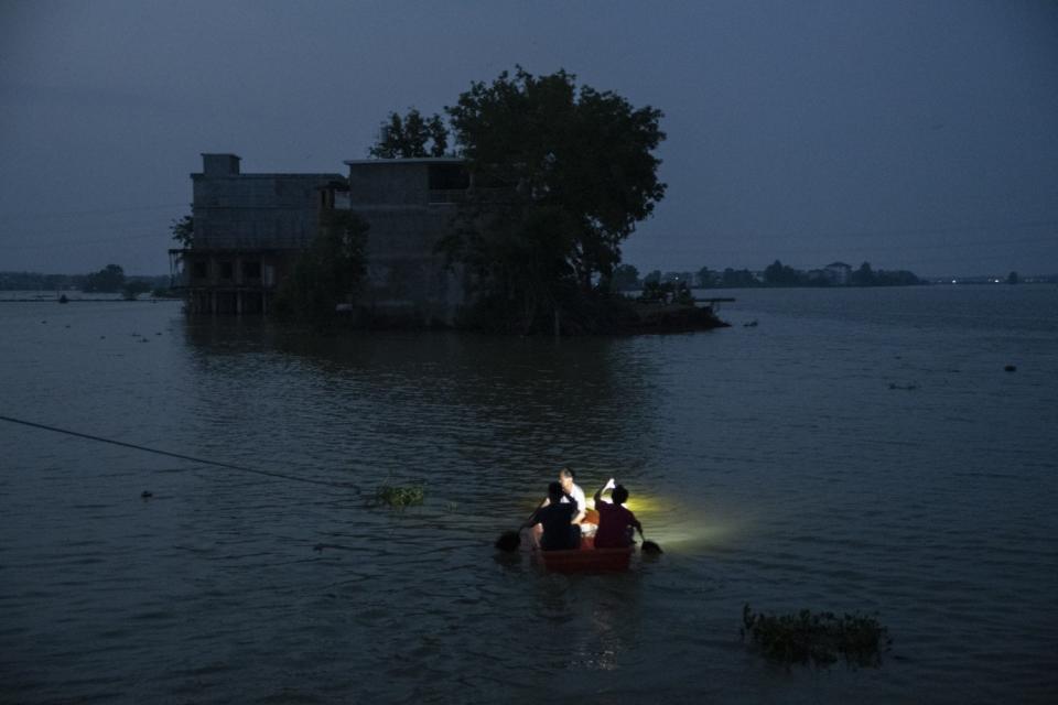 Villagers row a boat through the broken embankment.