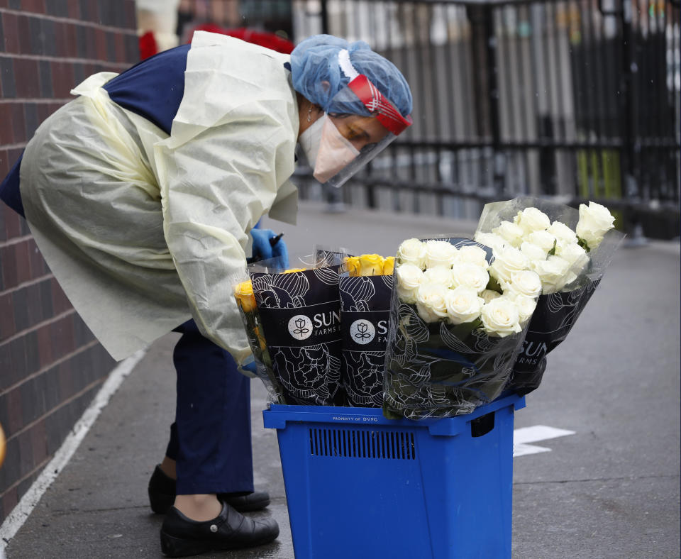 An emergency room nurse transports a bucket of donated flowers up a ramp leading to the ER outside Elmhurst Hospital Center in New York, Saturday, March 28, 2020. The hospital has been heavily taxed recently treating an influx of coronavirus patients. Currently New York leads the nation in the number of cases, according to Johns Hopkins University, which is keeping a running tally. (AP Photo/Kathy Willens)