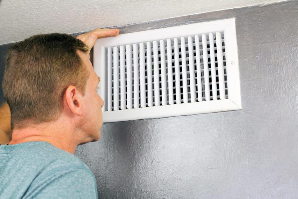 A man inspects a vent.