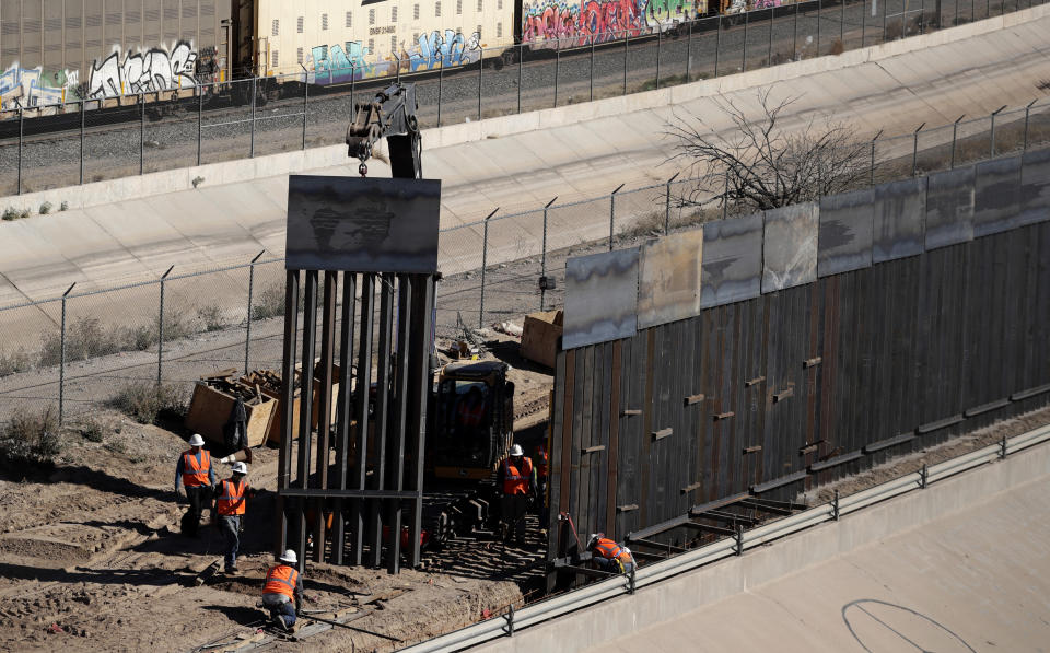 FILE - In this Jan. 22, 2019, file photo, workers place sections of metal wall as a new barrier is built along the Texas-Mexico border near downtown El Paso. The government is working on replacing and adding fencing in various locations, and Trump in February declared a national emergency to get more funding for the wall. (AP Photo/Eric Gay, File)