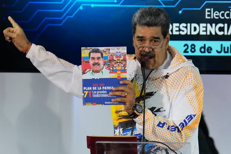 El presidente venezolano Nicolás Maduro sostiene un libro con su fotografía mientras habla en la Comisión Nacional Electoral, adonde llegó para formalizar su candidatura para postularse nuevamente a la presidencia en Caracas, Venezuela, el lunes 25 de marzo de 2024