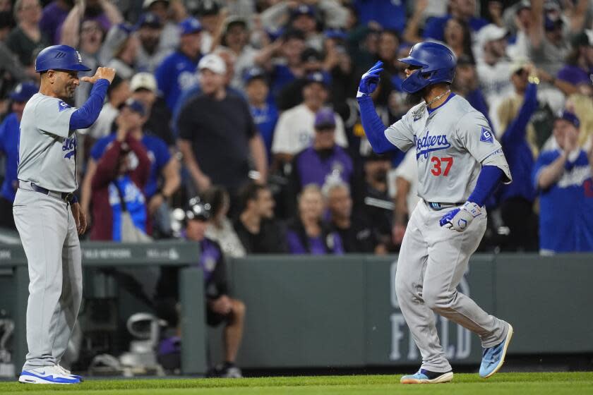 Los Angeles Dodgers' Teoscar Hernández, right, gestures to third base coach Dino Ebel after hitting a three-run home run against the Colorado Rockies during the ninth inning of a baseball game Tuesday, June 18, 2024, in Denver. (AP Photo/David Zalubowski)