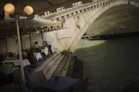 Tourists eat a meal on an almost empty restaurant terrace in Venice, Italy, Friday, Feb. 28, 2020. Venice in the time of coronavirus is a shell of itself, with empty piazzas, shuttered basilicas and gondoliers idling their days away. Venice, a UNESCO world heritage site, had already been brought to its knees last year, when near-record high tides flooded a lagoon city used to frequent spells of "aqua alta." (AP Photo/Francisco Seco)