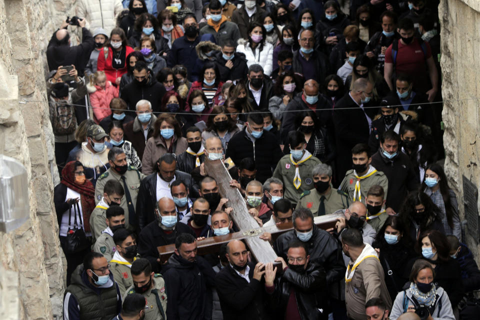 Cristianos cargan una cruz por la Vía Dolorosa durante una procesión del Viernes Santo rumbo a la Iglesia del Santo Sepulcro, donde según la tradición fue crucificado Jesucristo, el viernes 2 de abril de 2021 en la ciudad vieja de Jerusalén. (AP Foto/Mahmud Illean)