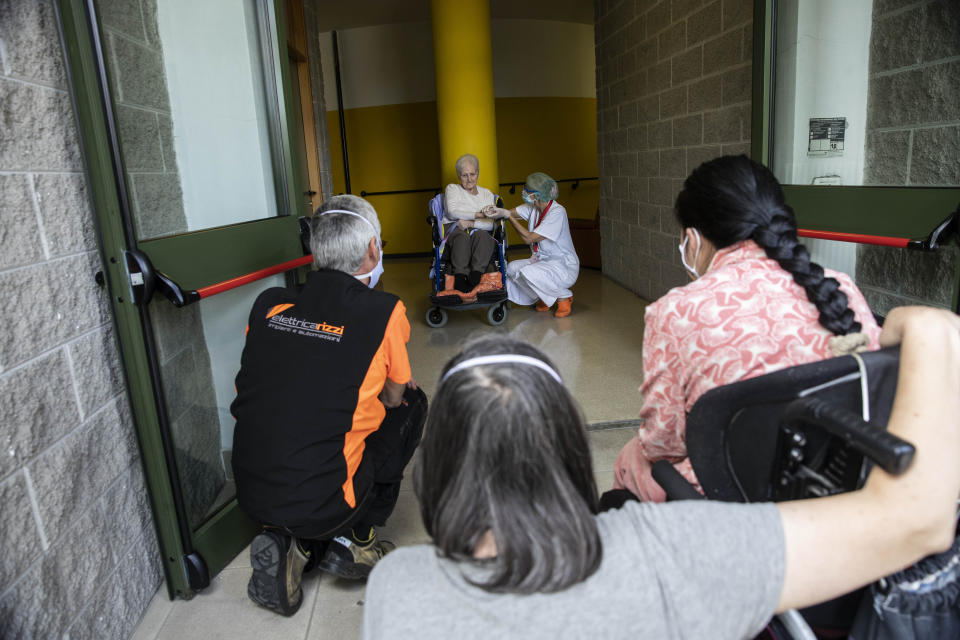 Albina Minelli, 92, sits in a wheelchair as she talks from safe distance with her family at the Martino Zanchi Foundation nursing home in Alzano Lombardo, Italy, Friday, May 29, 2020. Loved ones are being allowed to reunite with residents of the Martino Zanchi Foundation nursing home in the northern Italian town of Alzano. It comes after more than three months of separation and worry amid the coronavirus pandemic. Alzano, close to Bergamo, is the site of one of Italy's biggest outbreaks, centered around the town's hospital. (AP Photo/Luca Bruno)