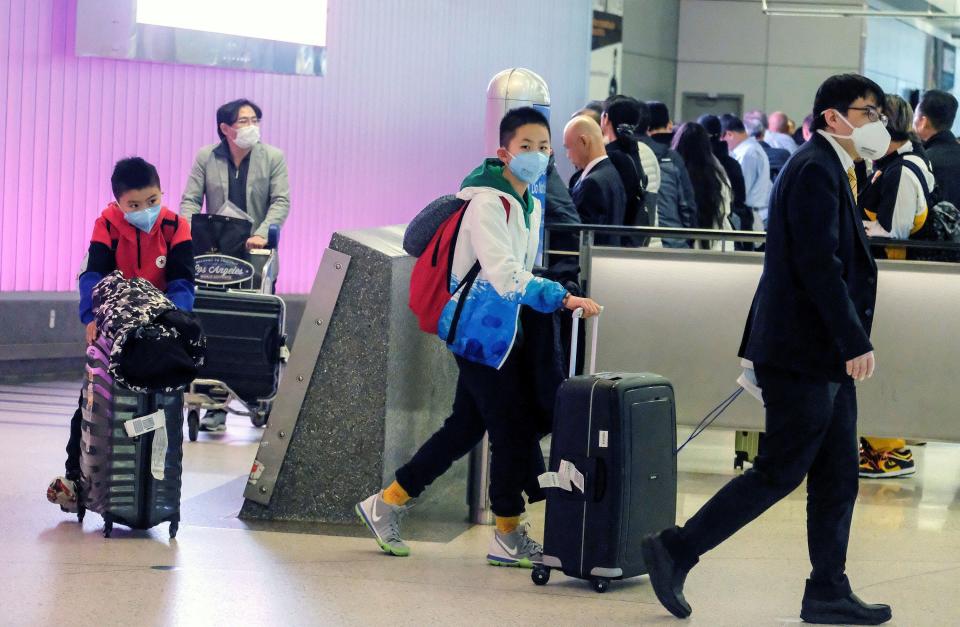 Passengers wearing face masks arrive at the Los Angeles International Airport from Shanghai, China, on Sunday after a positive case of the coronavirus was announced in the Orange County suburb of Los Angeles. (Photo: Ringo Chiu / Reuters)