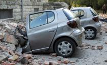 Destroyed cars stand next to a damaged building after an earthquake in Tirana