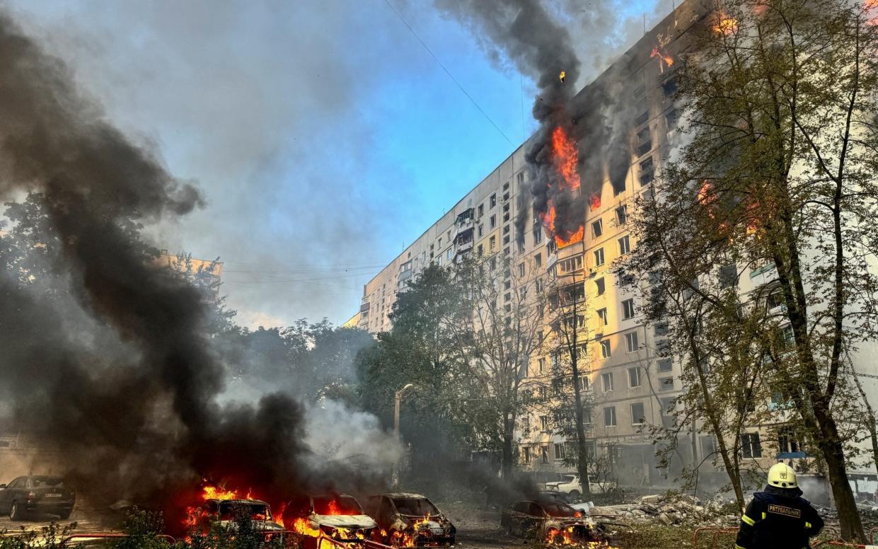 A firefighter looks at a burning building following a Russian guided bomb strike on Kharkiv