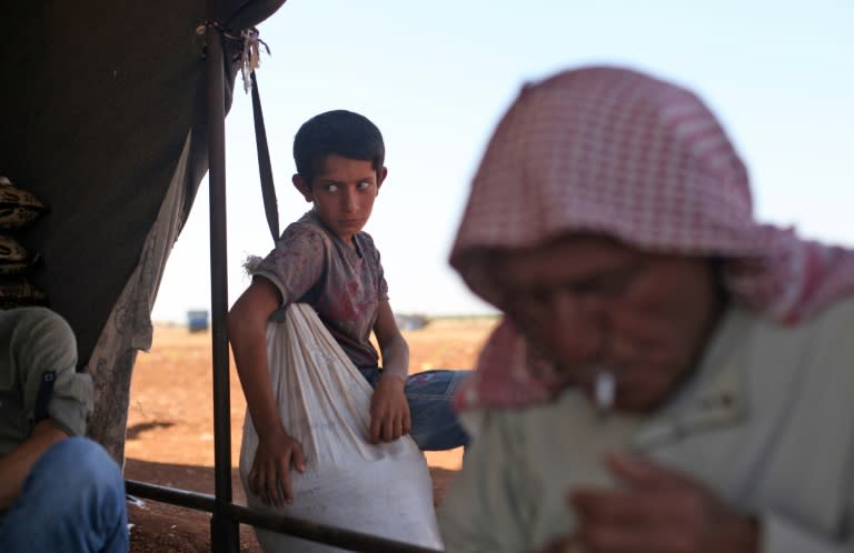 Civilians fleeing an expected Syrian government offensive on rebel-held areas of Idlib province sit outside a tent set up close to a Turkish military observation point near the village of Surman on September 5, 2018