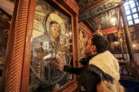 Milad Ayyad, a Palestinian Greek Orthodox Christian from Gaza, touches the icon of the Virgin and Child for a blessing at the Greek Basilica at the Church of the Nativity, where tradition says Jesus was born in Bethlehem, the occupied West Bank (AFP/HAZEM BADER)