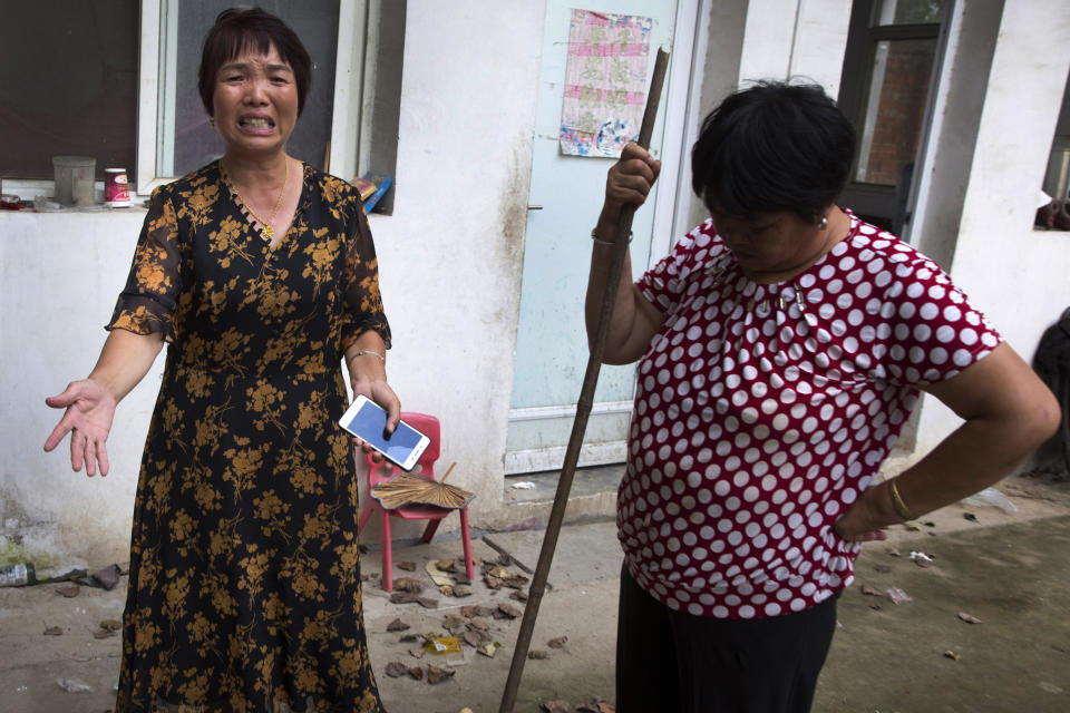In this July 11, 2018, photo, Xu Ying, left, stands with her neighbor at their home in Gucheng village in central China's Henan province. The AP spoke to the family Marip Lu, a young woman from Myanmar, accused of abusing her. The father, Li Qinggong, and mother, Xu Ying, (pictured) both denied Marip Lu had been abused or raped, and insisted she had not been purchased. But neither was able to explain how she'd ended up in their faraway village, or how she allegedly met and "married" their mentally disabled son, Li Mingming. (AP Photo/Ng Han Guan)