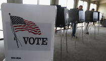 FILE - In this March 18, 2014 file photo, voters cast their ballots in Hinsdale, Ill. Microsoft announced Monday, May 6, 2019, an ambitious effort to make voting secure, verifiable and reliably auditable with open-source software that top U.S elections vendors say they will explore incorporating into new and existing voting equipment. (AP Photo/M. Spencer Green, File)