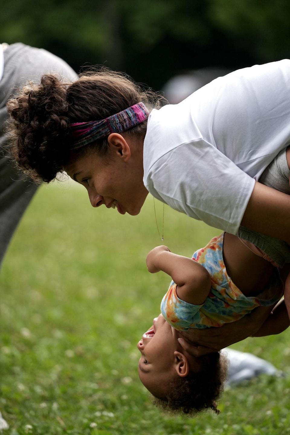 Raquel Williams does yoga with daughter Riot, 1, before the start of a walk involving members or Rise at Blacklick Woods Metro Park.