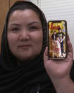 FILE - In this image from video, Zumret Dawut, a Uighur from China's western Xinjiang region, who was forcibly sterilized for having a third child after being released from a Xinjiang detention camp, holds a phone with a picture of her kids at her home in Woodbridge, Va., on Monday, June 15, 2020. For Dawut and other camp survivors who spoke out, the U.N.'s report on the mass detentions and other rights abuses against Uyghurs and other mostly Muslim ethnic groups in Xinjiang was the culmination of years of advocacy, and a much-welcome acknowledgement of the abuses they say they faced at the hands of the Chinese state. (AP Photo/Nathan Ellgren, File)