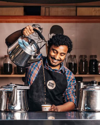 <p>Haydon Perrior</p> Haridev Chitturi, a staff member at the Spitalfields location of Chai Guys, demonstrates the art of pouring chai from a height, which cools down and froths the tea