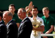 Tennis - Wimbledon - All England Lawn Tennis and Croquet Club, London, Britain - July 15, 2018 Serbia's Novak Djokovic waves to his family as he celebrates with the trophy after winning the men's singles final against South Africa's Kevin Anderson. REUTERS/Andrew Couldridge