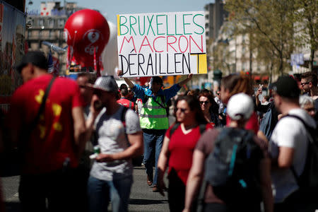 A man holds a placard reading "Brussels Macron derailed" during a demonstration against the French government's reform plans in Paris as part of a national day of protest, France, April 19, 2018. REUTERS/Benoit Tessier