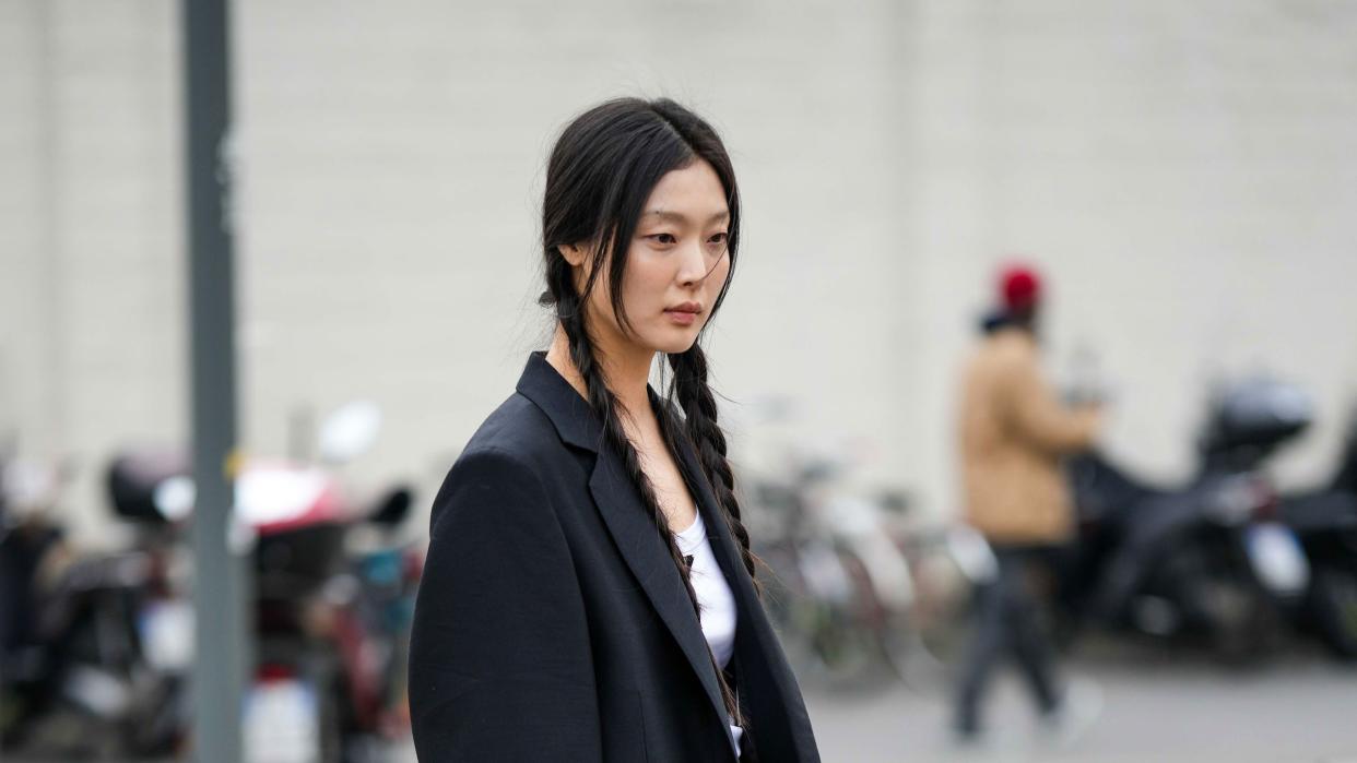 a person in a long coat and black shoes walking on a street