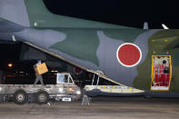 A member of Japan's Air Self-Defense Force carries a box into an airplane at an airbase in Komaki, central Japan, Thursday, Jan. 20, 2022, as they were preparing to take off for Australia on their way to Tonga to transport emergency relief, following Saturday's volcanic eruption near the Pacific nation. Japan's Defense Ministry said it would send emergency relief, including drinking water and equipment for cleaning away volcanic ash. (Kyodo News via AP)