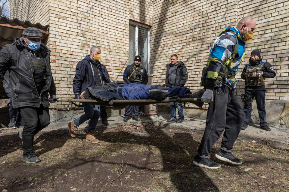 Ukrainian servicemen carry a dead body on a stretcher.