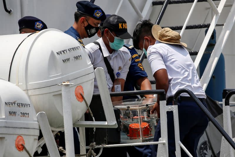 KNKT officials carry the Cockpit Voice Recorder (CVR) of Sriwijaya Air flight SJ 182 down a flight of stairs on an Indonesian Sea And Coast Guard vessel as it arrives at Tanjung Priok Port in Jakarta