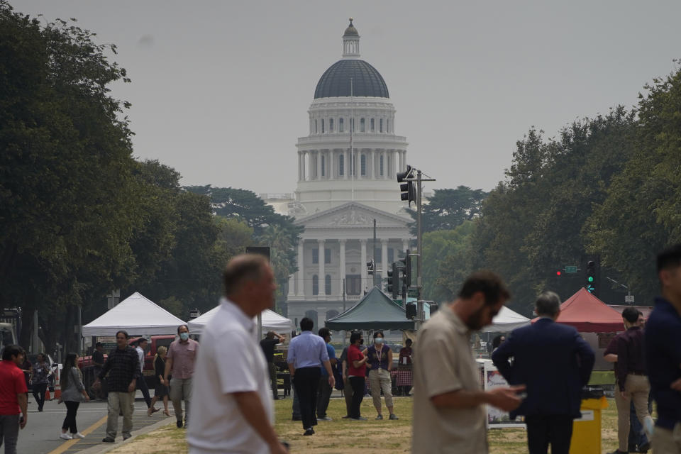 Smoke from area wildfires covers a farmers market and the California Capitol in Sacramento, Calif., Wednesday, July 28, 2021. (AP Photo/Rich Pedroncelli))