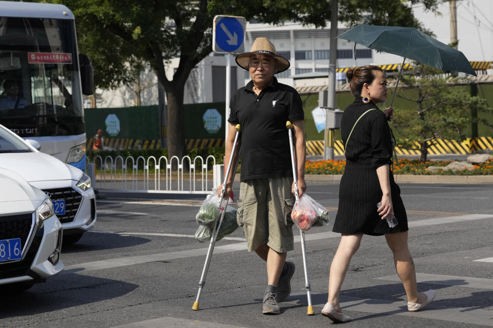 A man on crutches crosses the road with his groceries in Beijing, Monday, July 17, 2023. China's economy grew at a 6.3% annual pace in the April-June quarter, much lower than analysts had forecast given the slow pace of growth the year before. (AP Photo/Ng Han Guan)