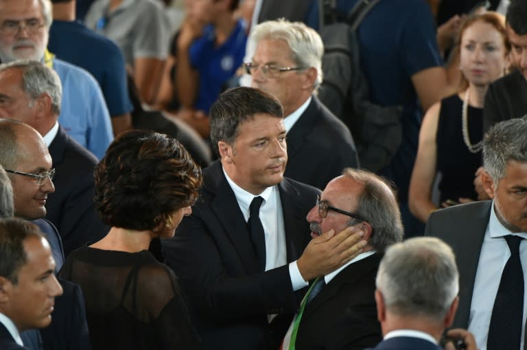 Italy's Prime Minister Matteo Renzi (C) embraces Arquata's mayor Leandro Petrucci during a funeral service in a gymnasium in Ascoli Piceno, central Italy on August 27, 2016, three days after a 6.2-magnitude earthquake struck the region