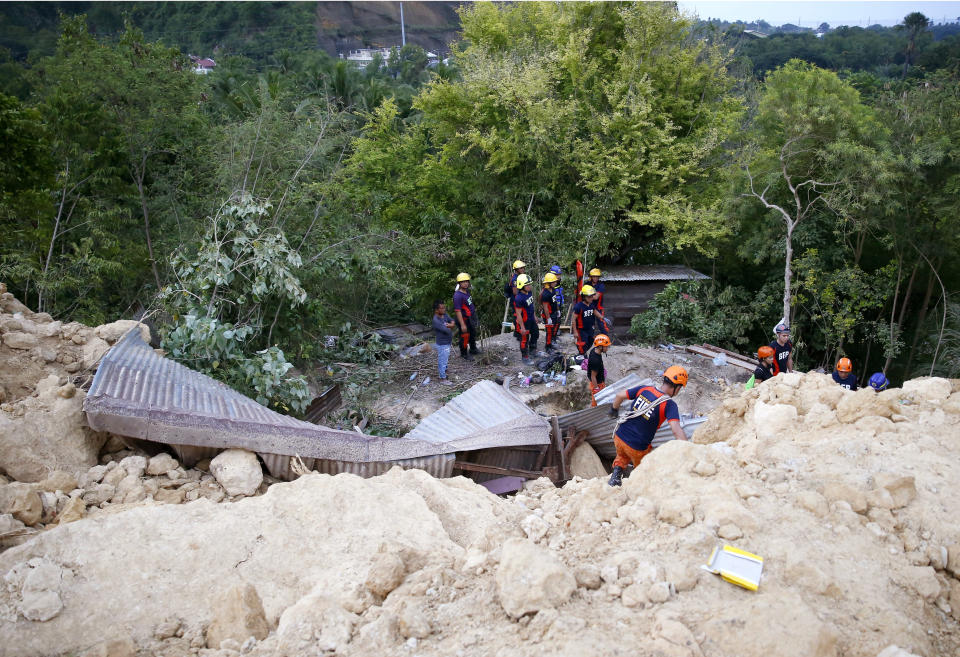 Rescuers dig through the rubble to search for possible survivors, with some sending cellphone text messages pleading for help, following a landslide that buried dozens of homes in Naga city, Cebu province central Philippines on Thursday Sept. 20, 2018. A landslide set off by heavy rains buried homes under part of a mountainside in the central Philippines on Thursday, and several people are feared buried, including two who sent text messages seeking help. (AP Photo/Bullit Marquez)