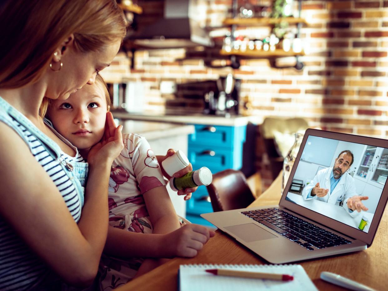 Close up of a mother and daughter consulting with their doctor over a video call on their laptop