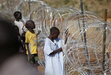 Internally displaced boys stand next to barbed wire inside a United Nations Missions in Sudan (UNMIS) compound in Juba December 19, 2013. REUTERS/Goran Tomasevic