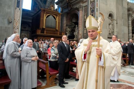 Archbishop Konrad Krajewski blesses faithful during a ceremony in Saint Peter's Basilica at the Vatican September 17, 2013. Picture taken September 17, 2013. Vatican Media/Handout via REUTERS