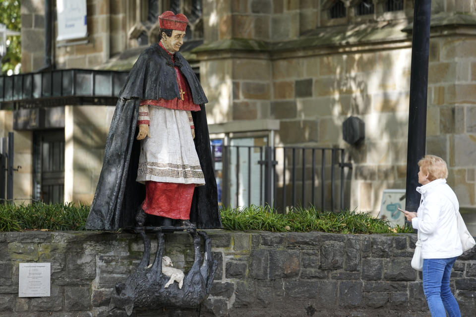 A woman watches the monument of German cardinal Franz Hengsbach beside the cathedral in the city center of Essen, western Germany, Friday, Sept. 22, 2023. The Catholic Church is investigating allegations of sexual abuse by the late cardinal over 30 years after his death. (AP Photo/Martin Meissner)