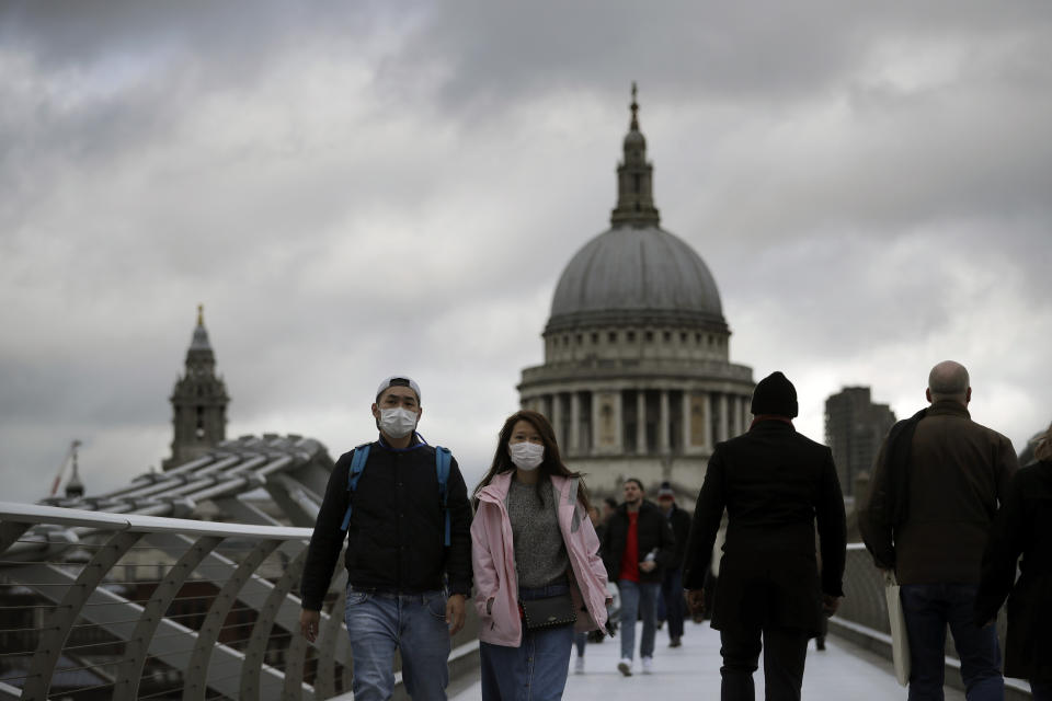 People wearing face masks walk across the Millennium footbridge backdropped by the dome of St Paul's Cathedral in London, Tuesday, March 10, 2020. Starkly illustrating the global east-to-west spread of the new coronavirus, Italy began an extraordinary, sweeping nationwide travel ban on Tuesday while in China, the diminishing threat prompted the president to visit the epicenter and declare: ""We will certainly defeat this epidemic." (AP Photo/Matt Dunham)