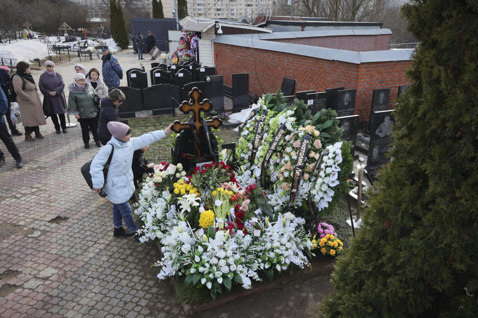 A woman touches a cross at the grave of Russian opposition leader Alexei Navalny on the fortieth day after his death as per Orthodox tradition at the Borisovskoye Cemetery, in Moscow, Russia, Tuesday, March 26, 2024. (AP Photo/Vitaly Smolnikov)