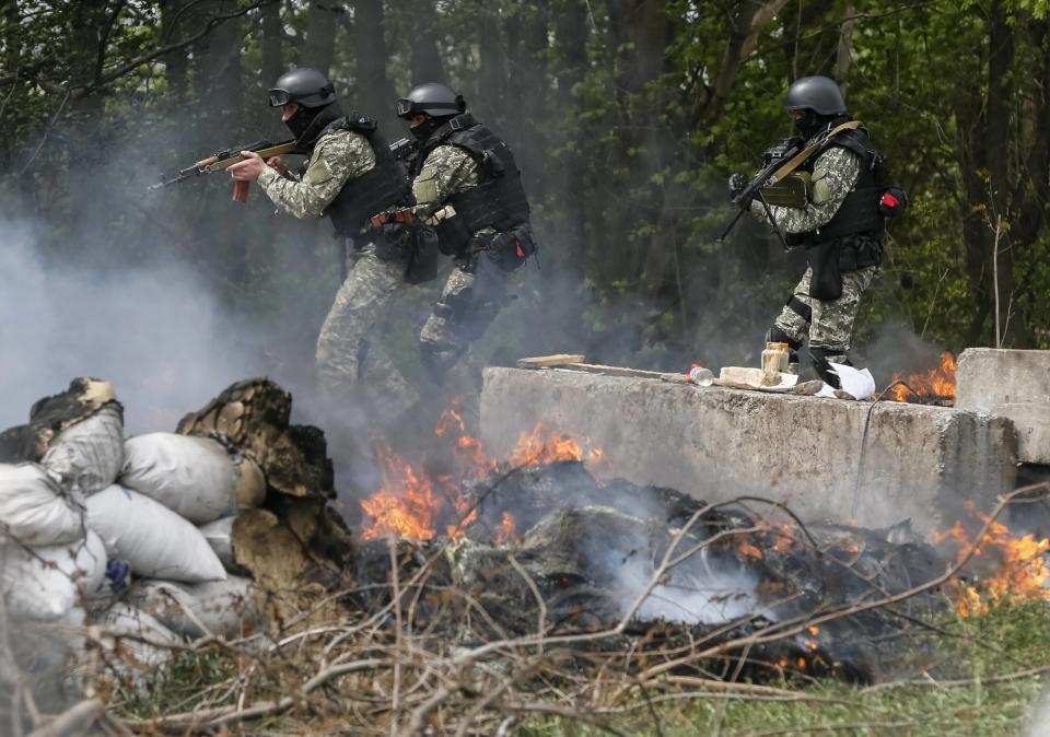 Oficiales de las fuerzas de seguridad ucranianas desplegados en un operativo en uno de los puntos de control que fue incendiado por los insurgentes pro rusos cerca de Slaviansk este 24 de abril de 2014. (REUTERS/Gleb Garanich)