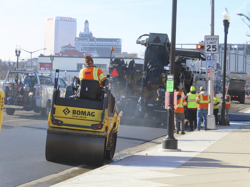 Workers repave a section of Atlantic Avenue in Atlantic City, N.J. on Dec. 13, 2023, as part of a project to reduce the main road through the gambling resort from four lanes to two. Federal and state funds that paid for the $24 million repaving and traffic light synchronization project also require a pedestrian safety component, in this case reducing the size of the roadway. (AP Photo/Wayne Parry)