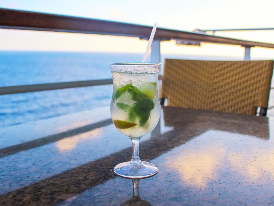 Cocktail with a straw on cruise table overlooking the water