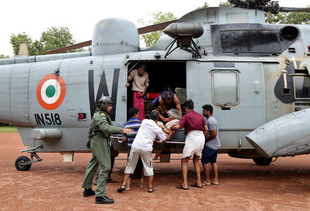 People help a woman disembark from an Indian Navy helicopter at a relief camp after being rescued from a flooded area in Kerala, August 17, 2018. REUTERS/Sivaram V