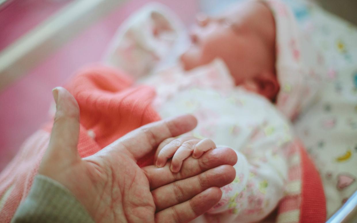 Newborn baby holding on to Mothers hand - Sally Anscombe /Getty Images