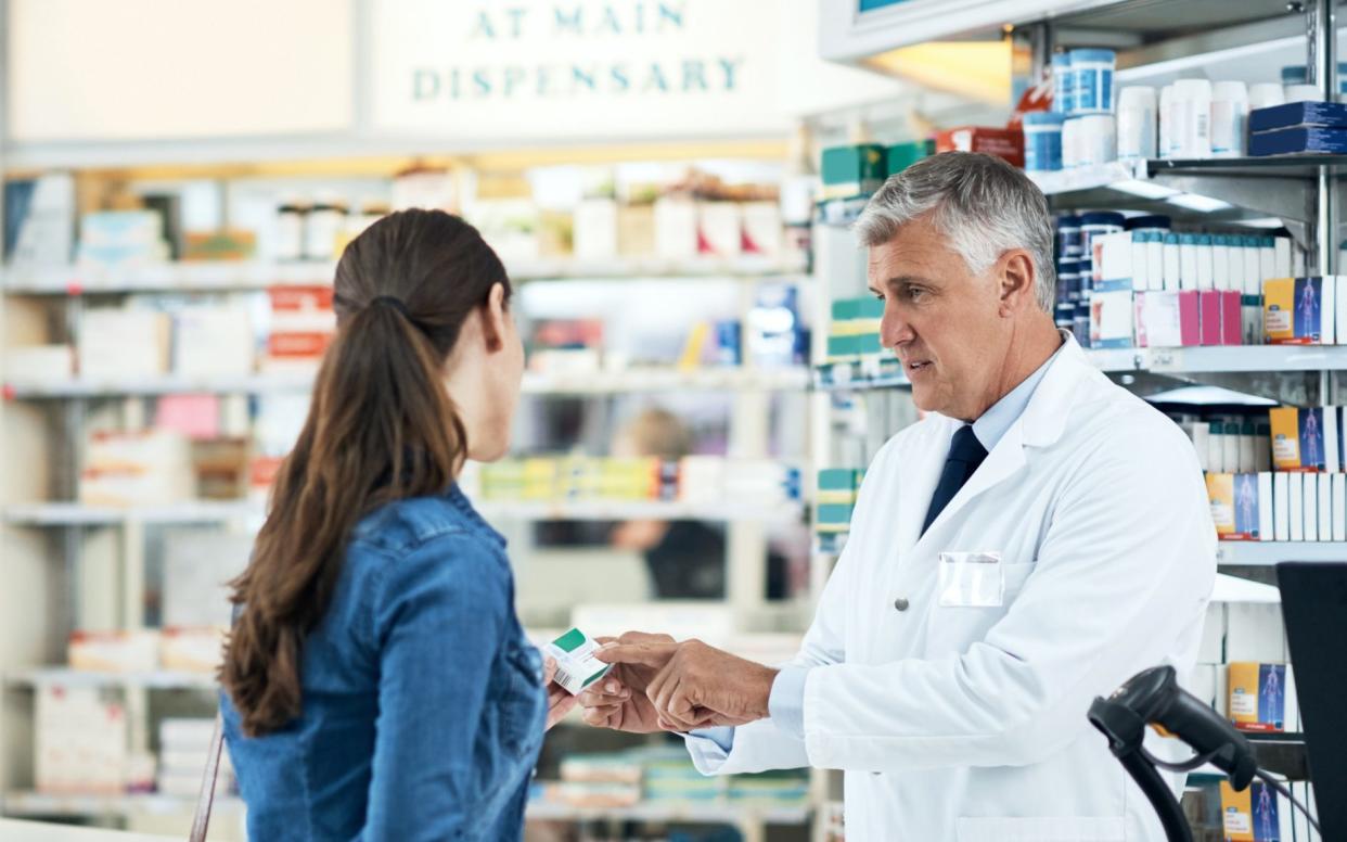 A pharmacist assists a young woman in a chemist - shapecharge/E+