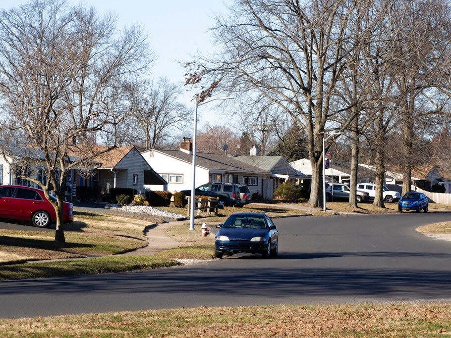 a car driving down a street lined with houses in in Levittown, Pennsylvania