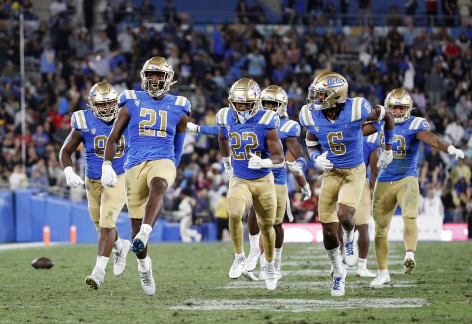 UCLA linebacker JonJon Vaughns celebrates with teammates after intercepting a pass.